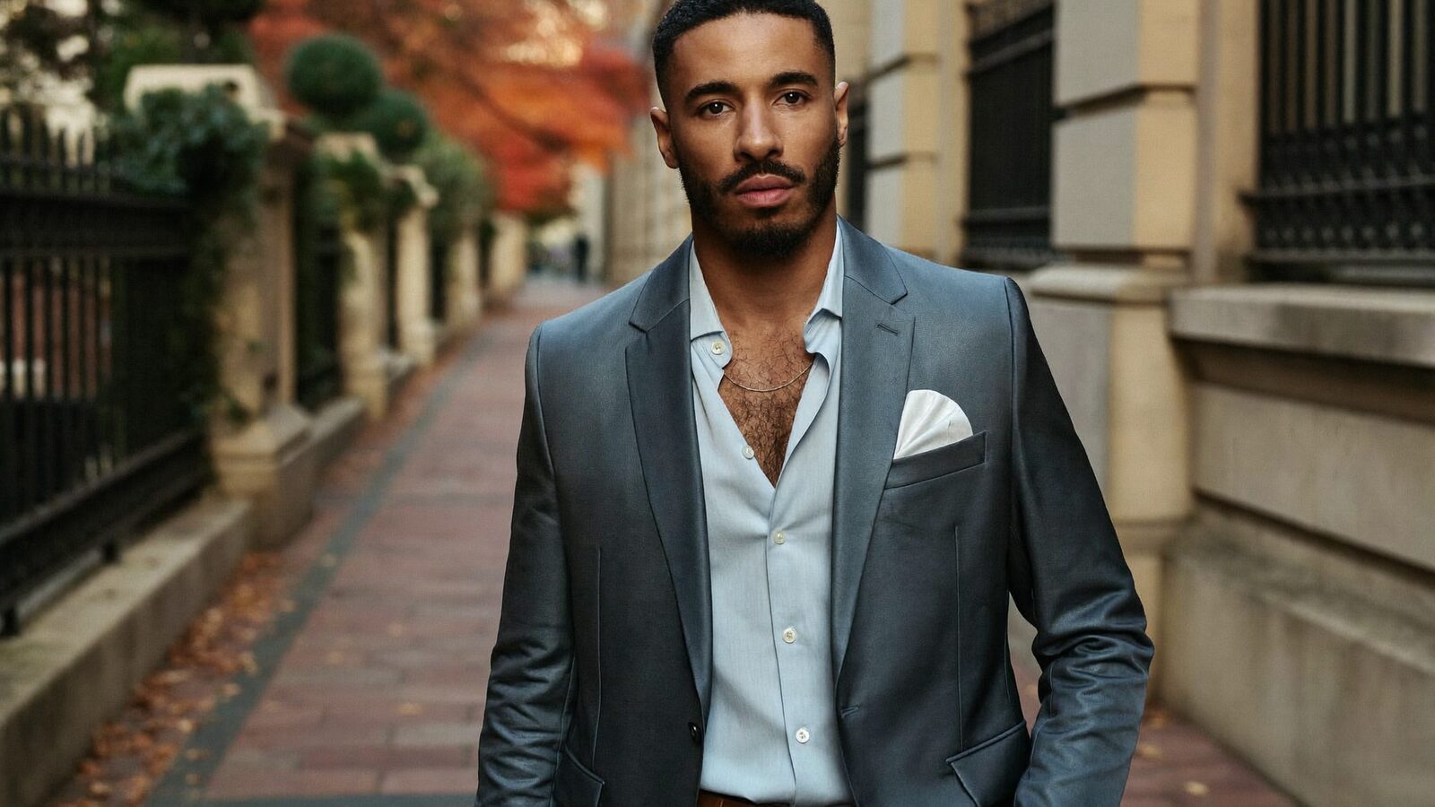 Well-dressed man with a full, natural hairline on a brick sidewalk in autumn