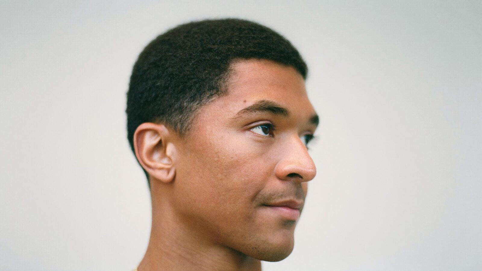 Profile portrait of a man with a natural, well-defined short hairline