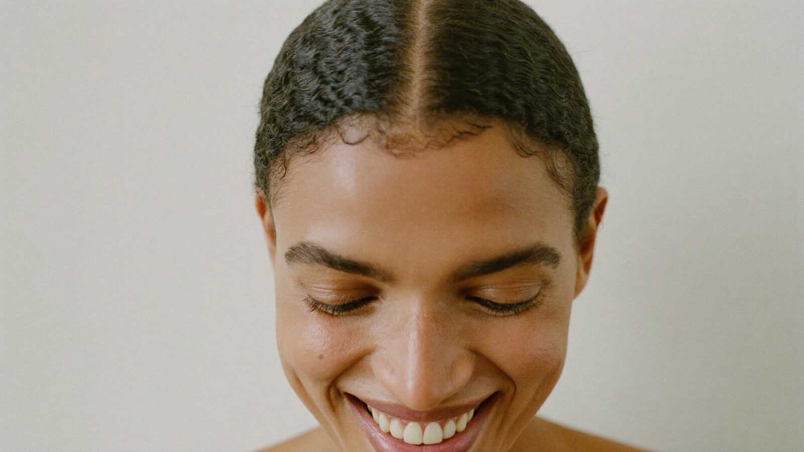 Smiling woman with a soft, natural hairline and her hair pulled back